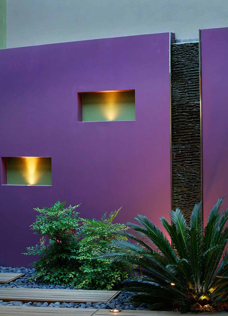 coloured light wall in subiaco courtyard with decking and pebbles