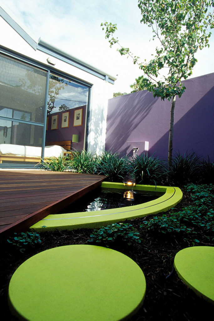 bold little courtyard with brightly coloured circular steppers and D shaped pond
